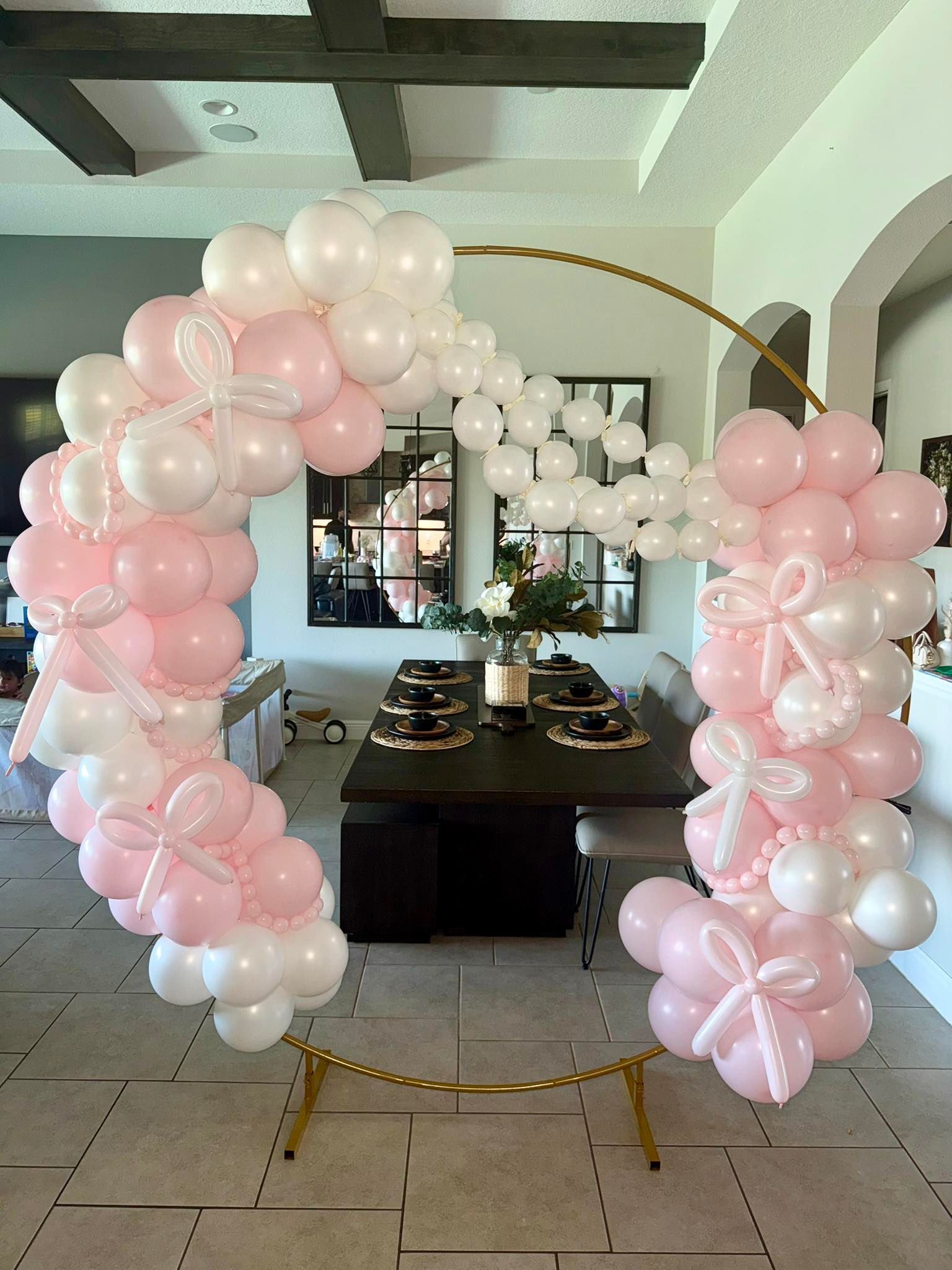 A room filled with pink and white balloons and a table.