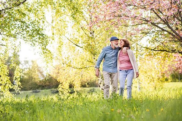 Senior Couple Walk Outside in Spring Nature Under Blossoming Trees — KS & MO — Leary & Associates