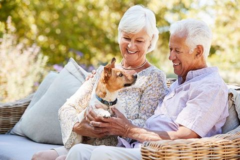 Happy Senior Couple Sitting with a Pet Dog — KS & MO — Leary & Associates