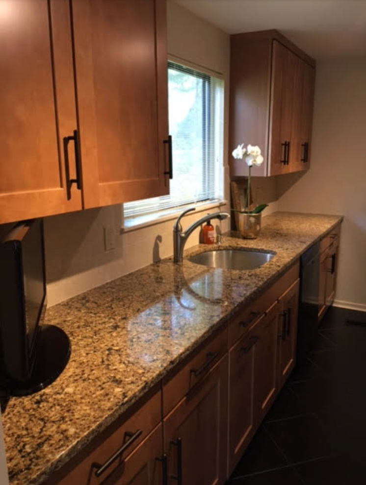 Kitchen with brown cabinets, granite countertop, and sink beneath a window.