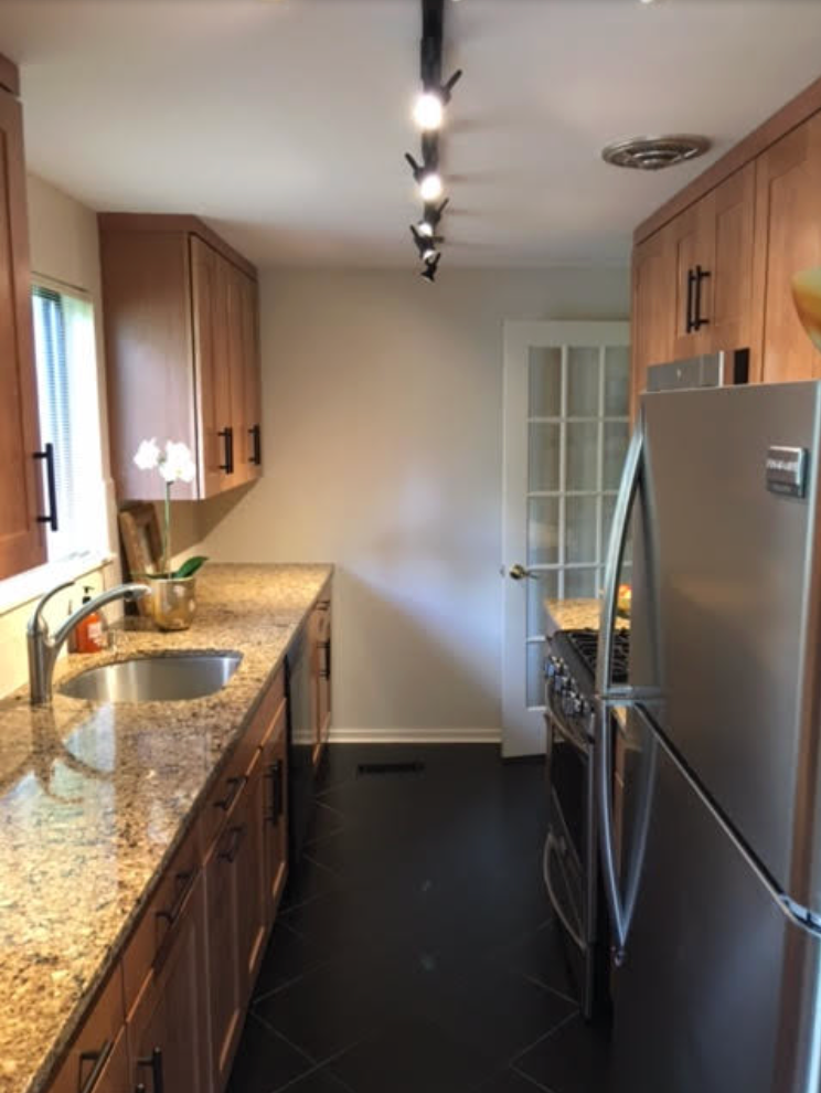 Kitchen with wood cabinets, granite countertops, stainless steel appliances, and a dark tiled floor.