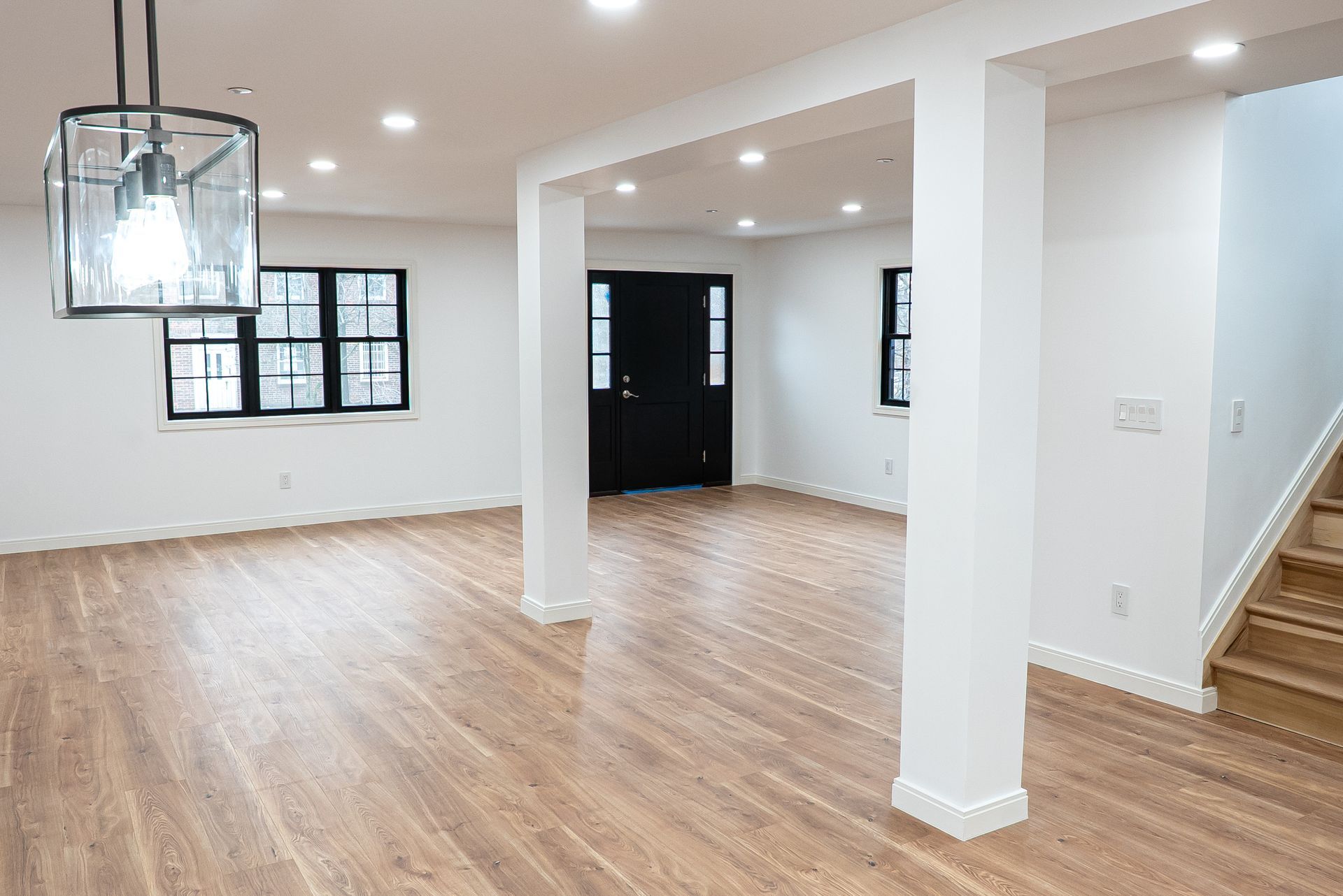 An empty basement with hardwood floors and white walls