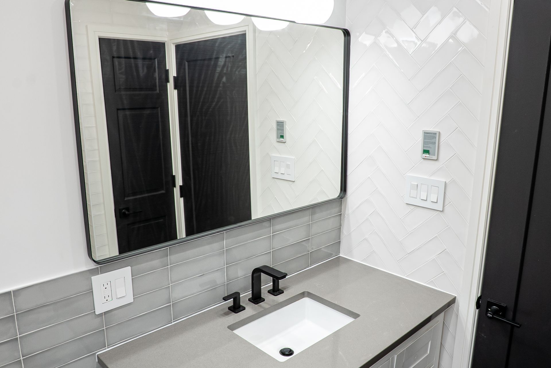 A bathroom with a sink, mirror and black doors