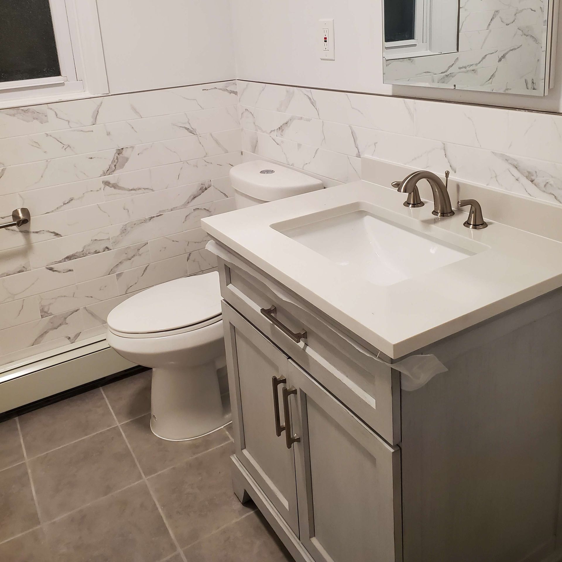 A bathroom with a toilet a sink and a mirror