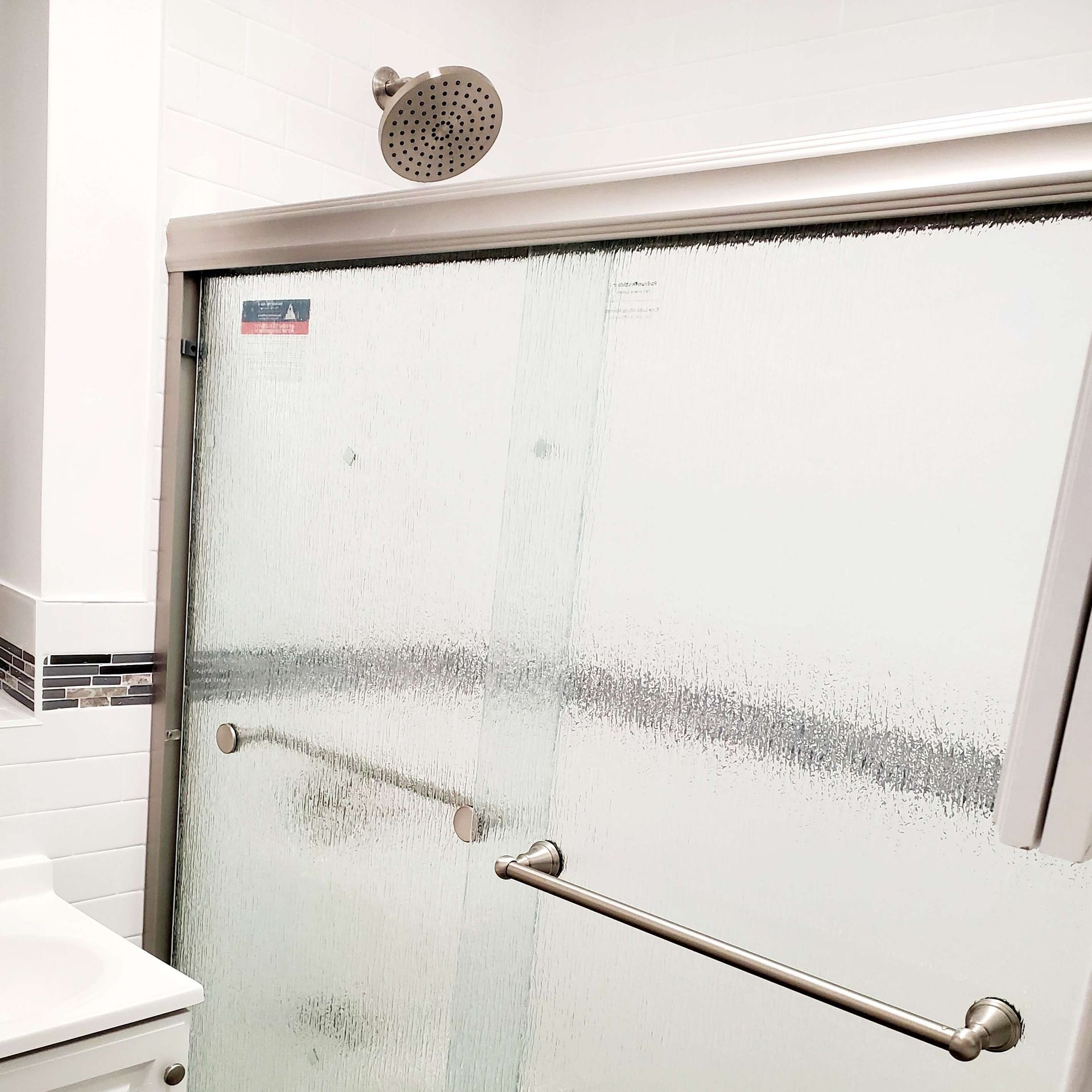 A bathroom with a sliding glass shower door and a shower head