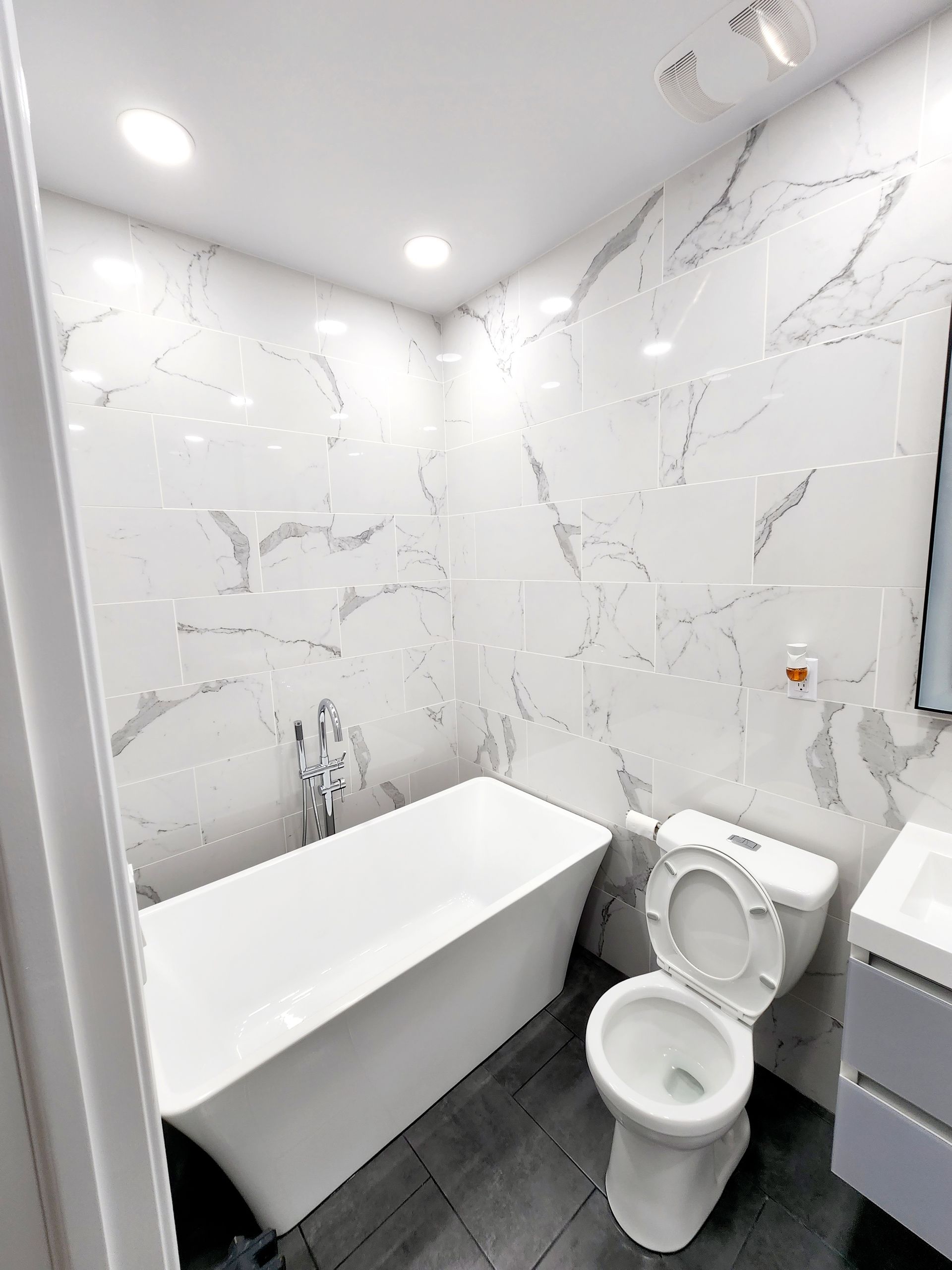 A bathroom with a tub, toilet, sink and mirror