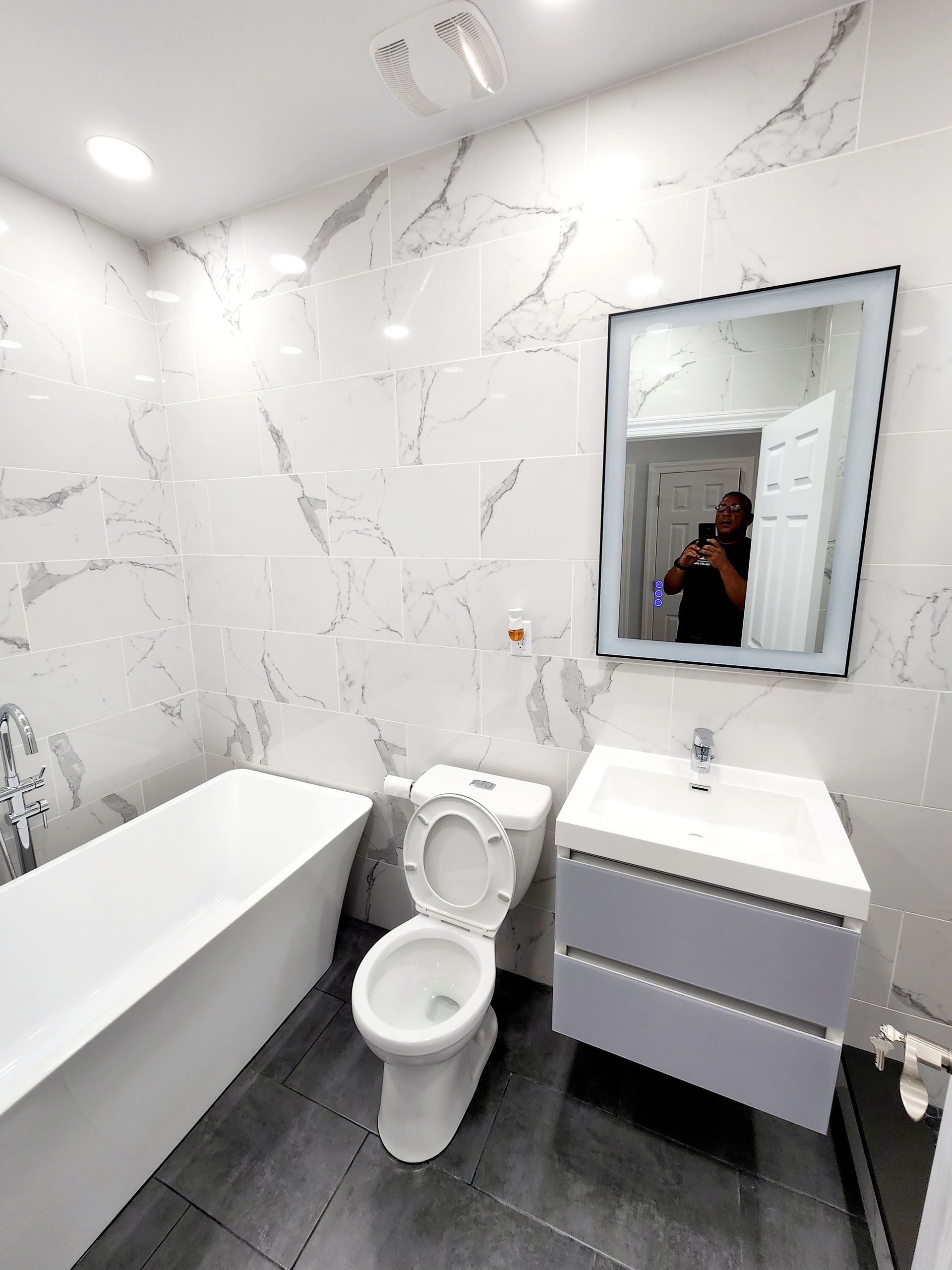 A bathroom with a toilet, sink, bathtub and mirror