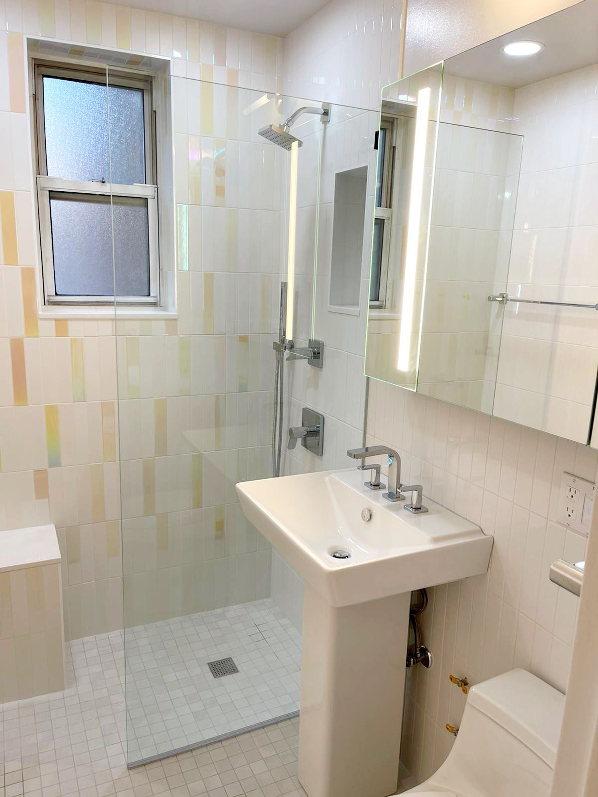 A bathroom with a sink, toilet, shower and mirror