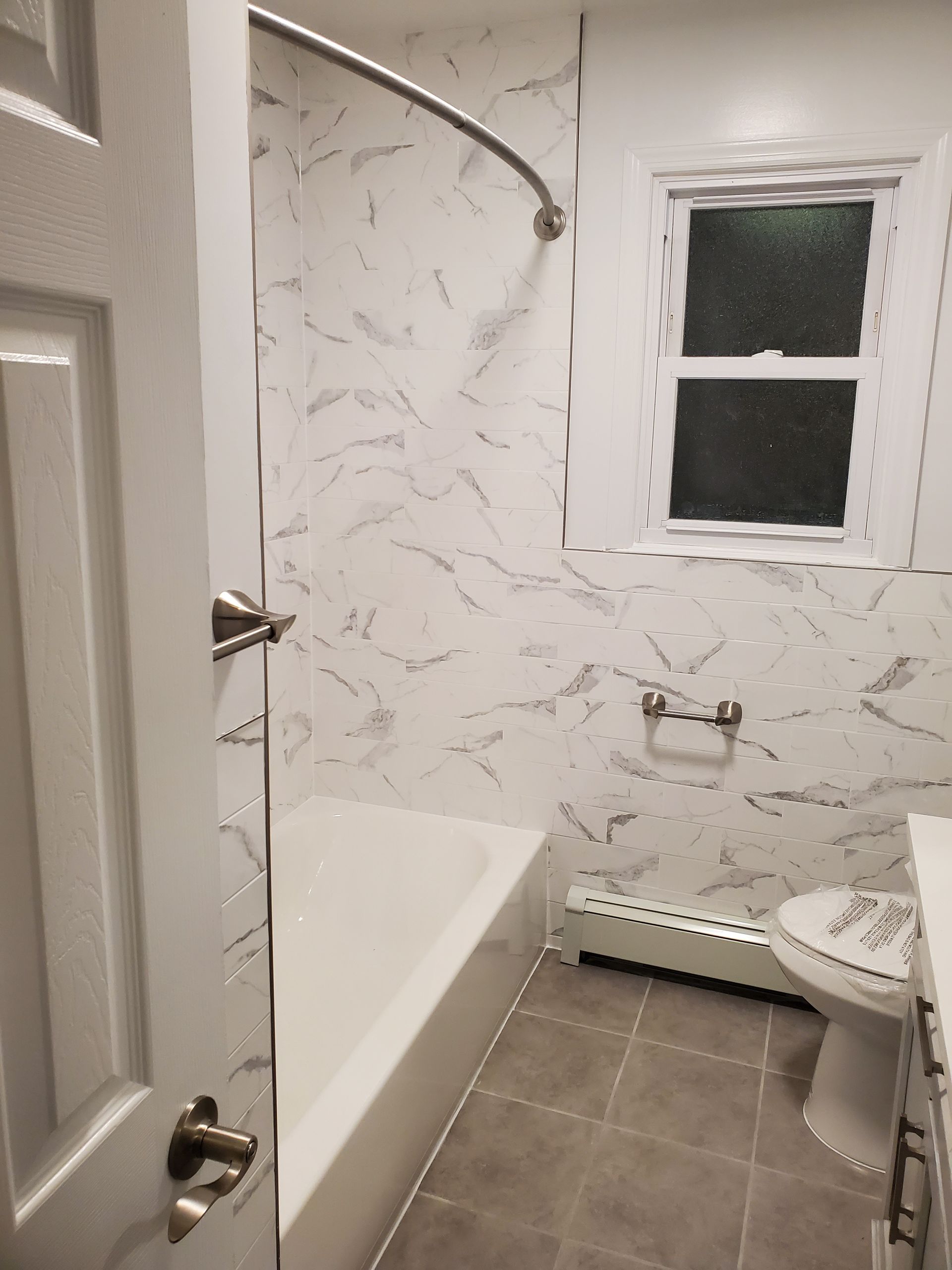 A bathroom with a tub, toilet, sink and window