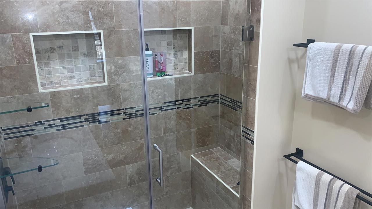 A bathroom with a walk in shower with a glass door