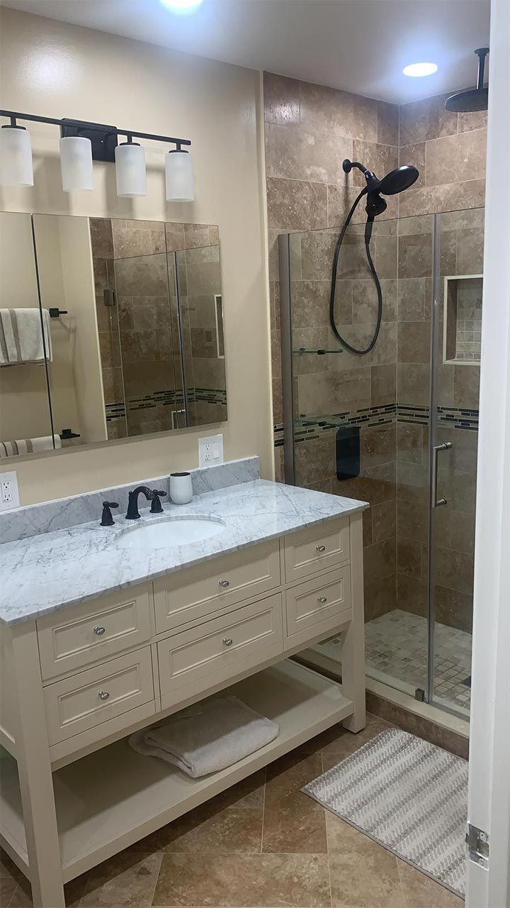 A bathroom with a sink, mirror, and walk in shower