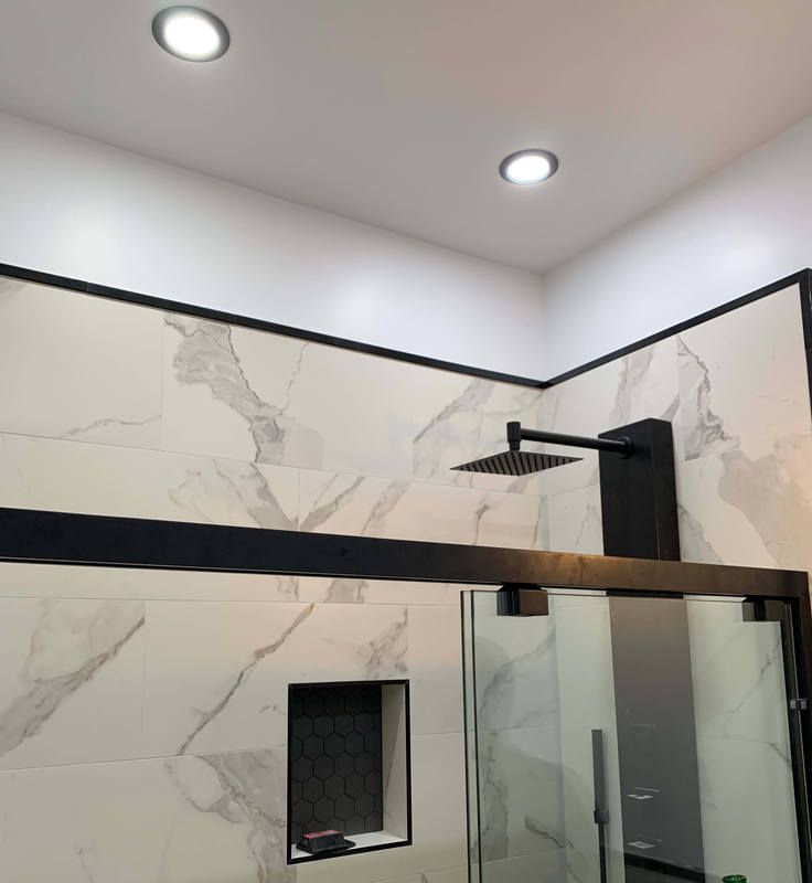A bathroom with marble walls and a black shower head