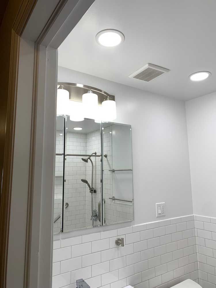 A bathroom with a toilet, sink, shower and mirror