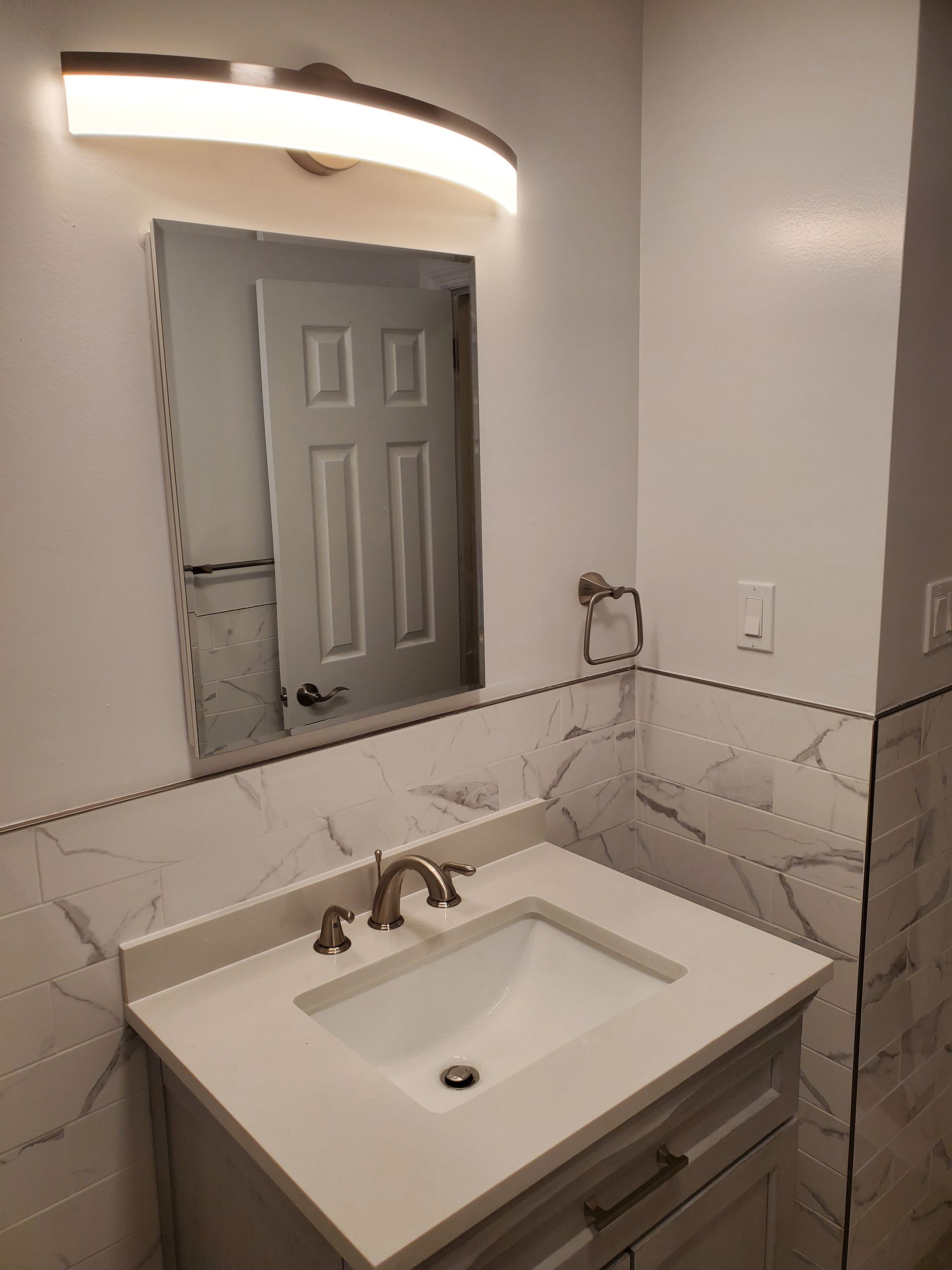 A bathroom with a sink, mirror and light
