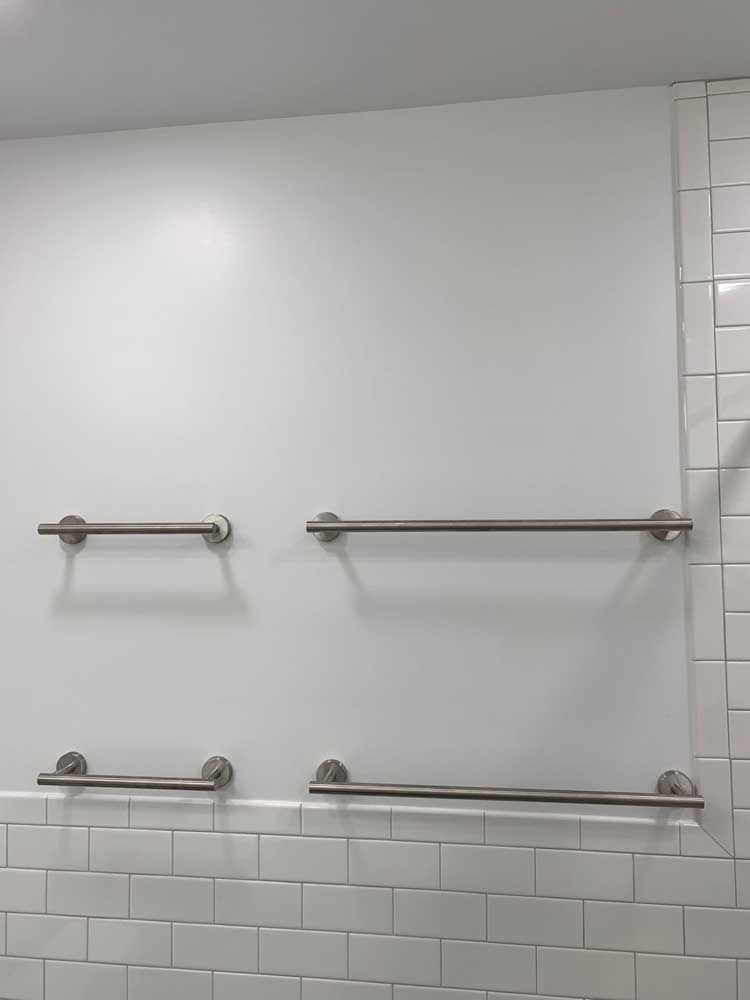 Three towel bars are hanging on a white wall in a bathroom