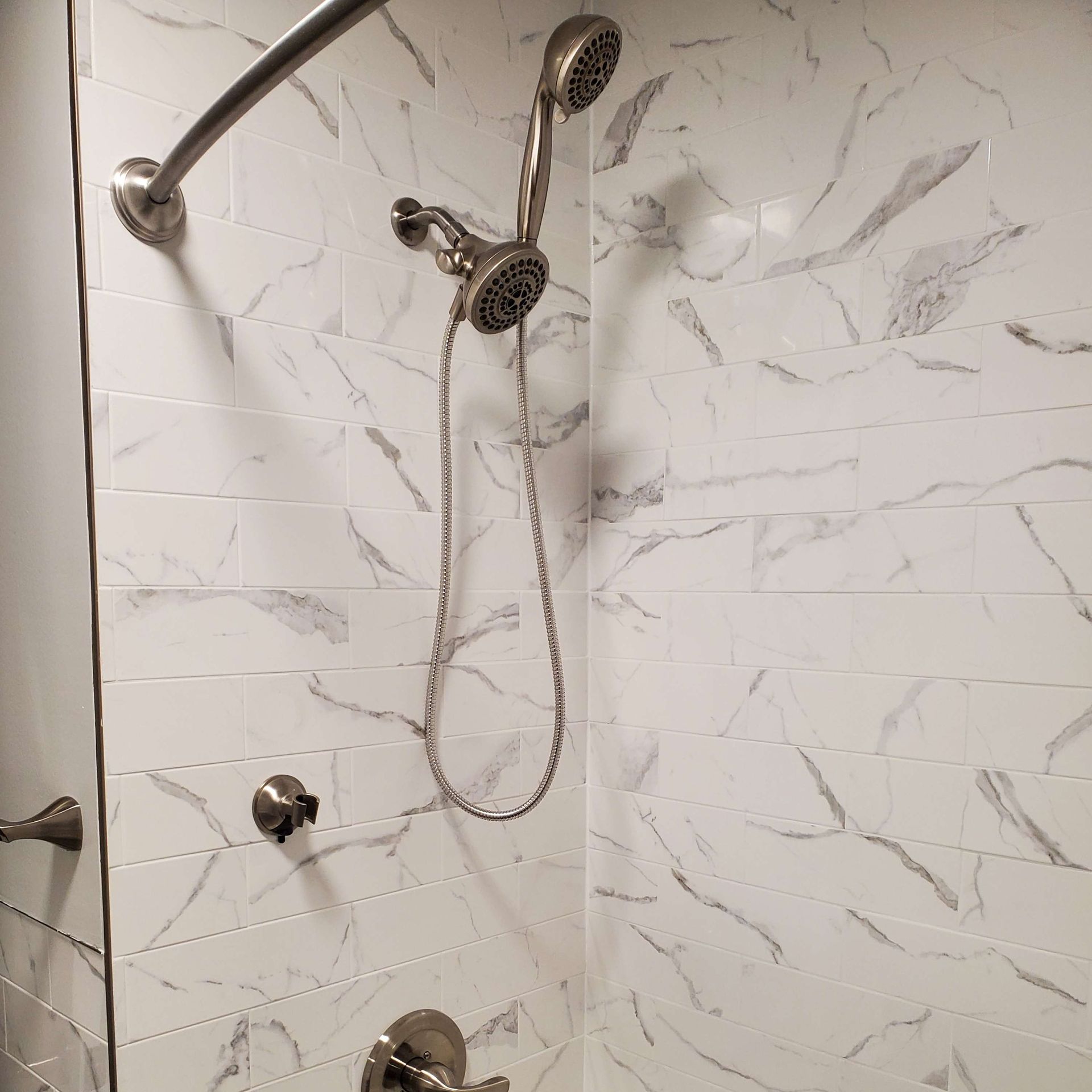 A shower with two shower heads and a marble wall