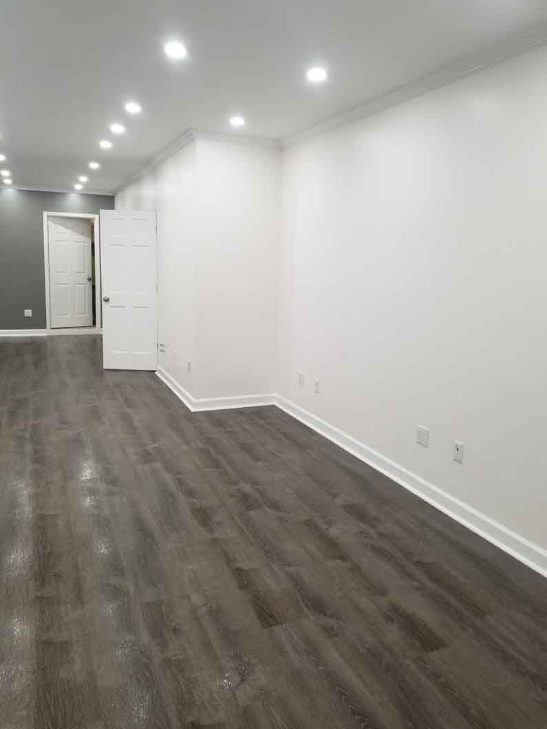 A large empty room with hardwood floors and white walls