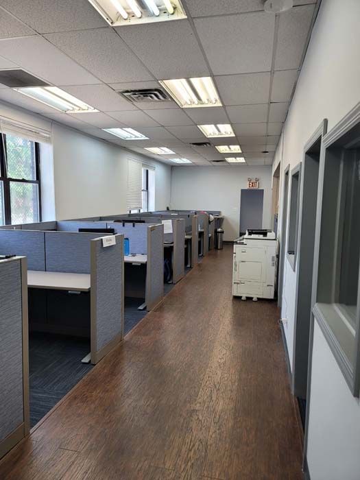 A long hallway in an office with cubicles and a printer