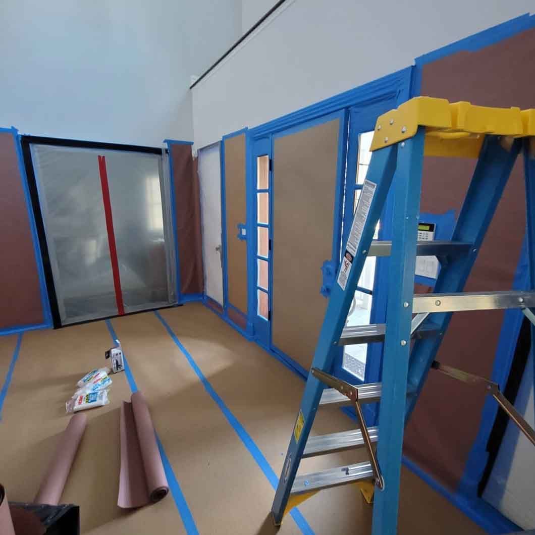 A blue ladder is in a room with blue tape on the floor