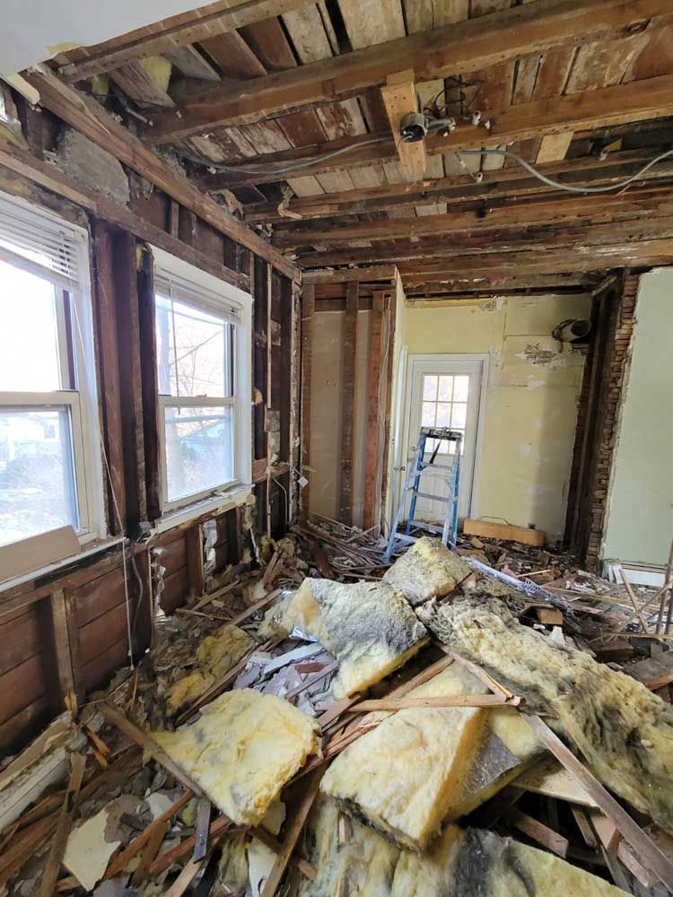 A room with a lot of junk in it and a ladder