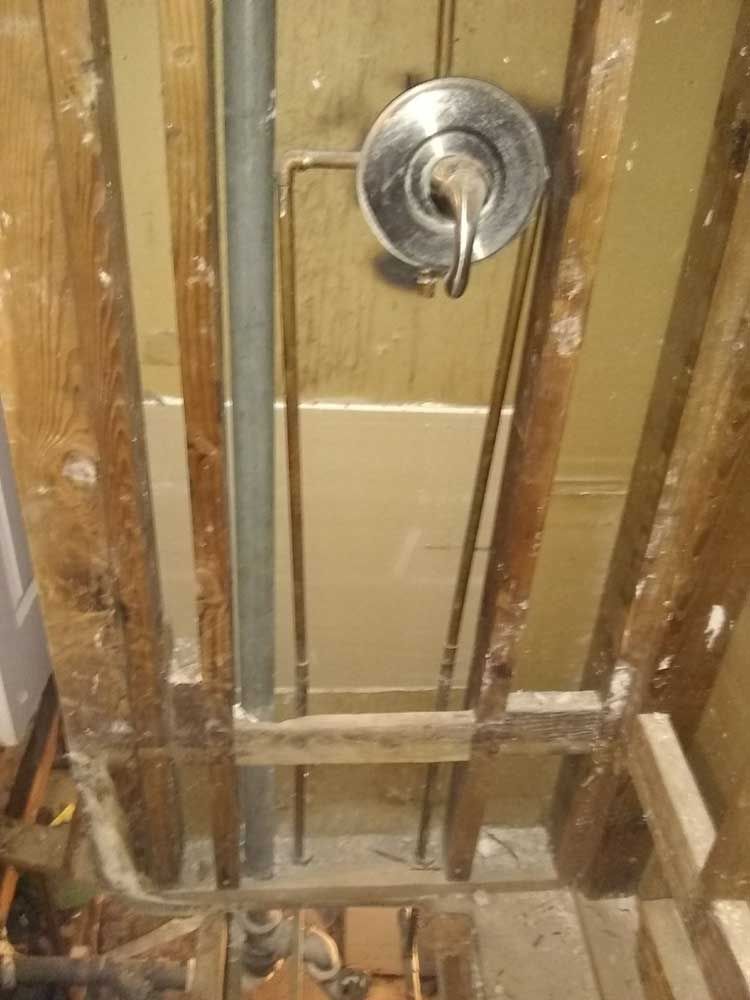 A shower head is hanging from the ceiling of a bathroom under construction