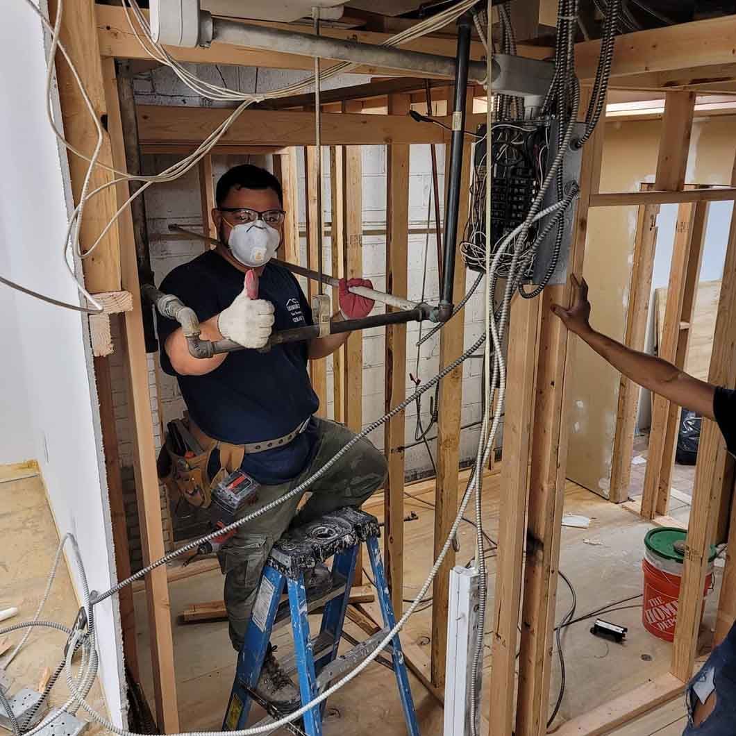 A man wearing a mask is standing on a ladder in a room