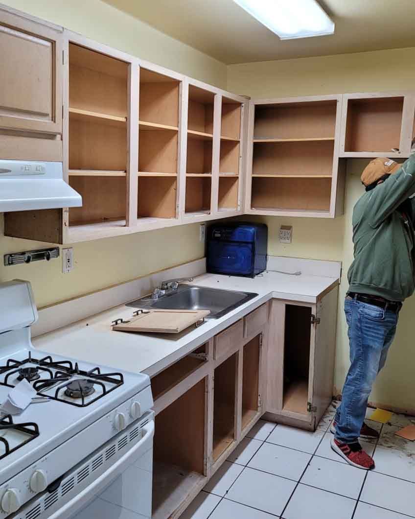 A man is standing in a kitchen with a stove and a sink