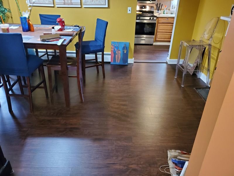 A dining room with a table and chairs and a kitchen in the background