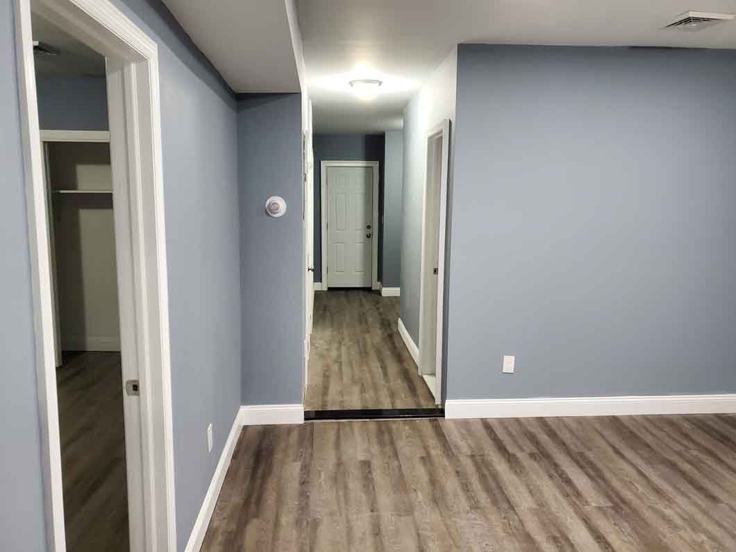 A hallway with blue walls and a wooden floor