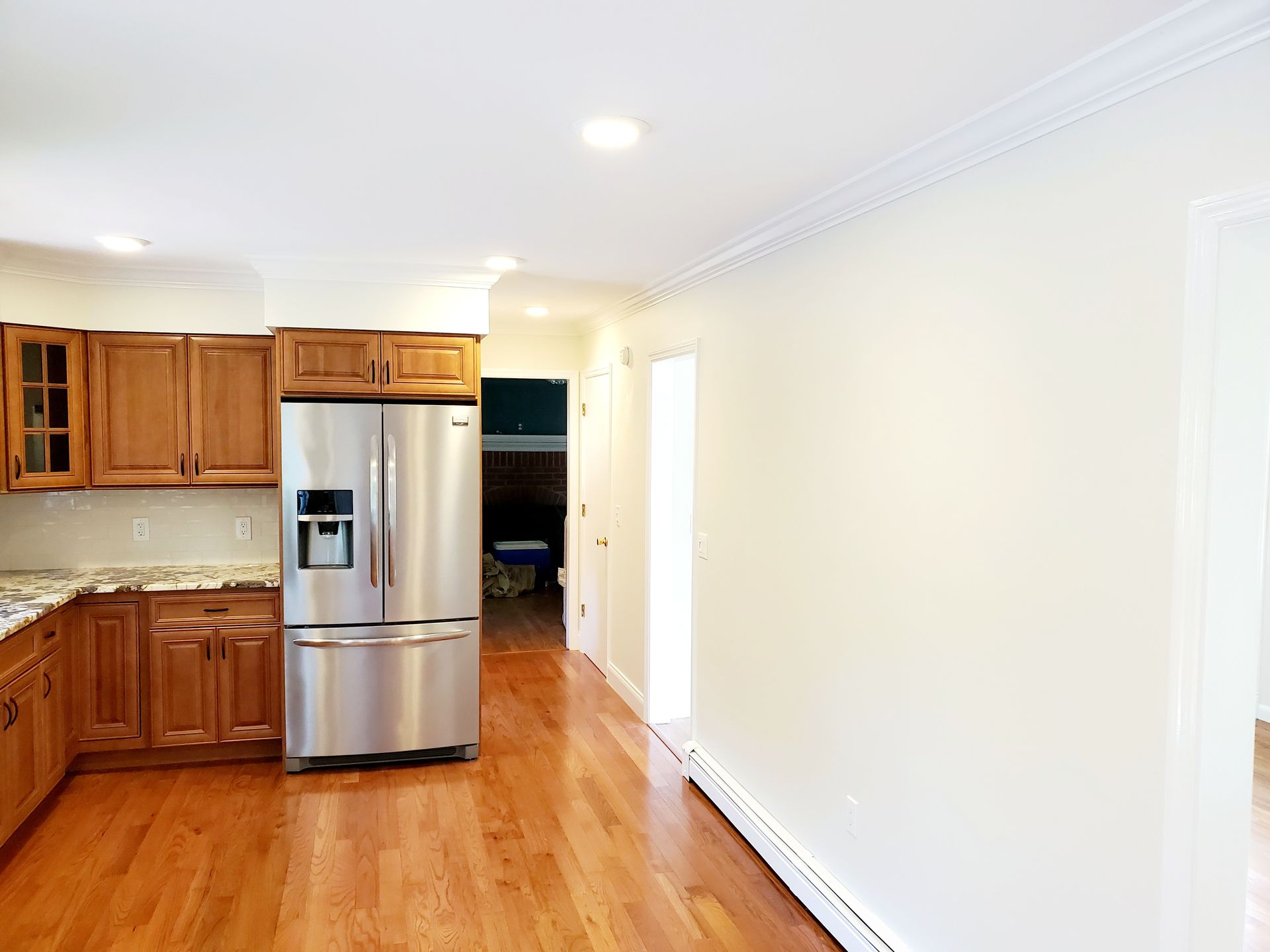 An empty kitchen with wooden cabinets and a stainless steel refrigerator