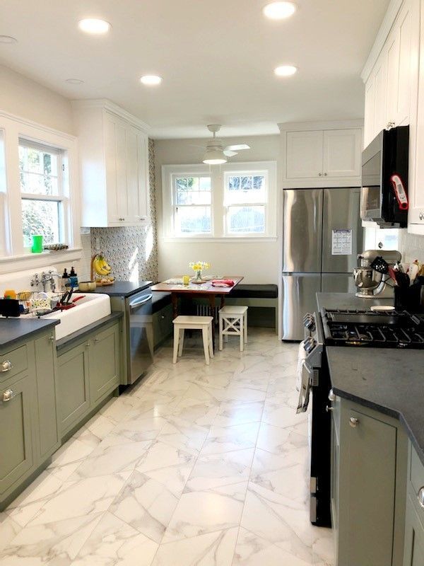 A kitchen with white cabinets, a stove, a refrigerator, a sink, and a table