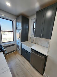 A kitchen with a sink, washer and dryer, and stainless steel appliances