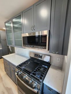 A kitchen with a stove, oven, microwave and cabinets