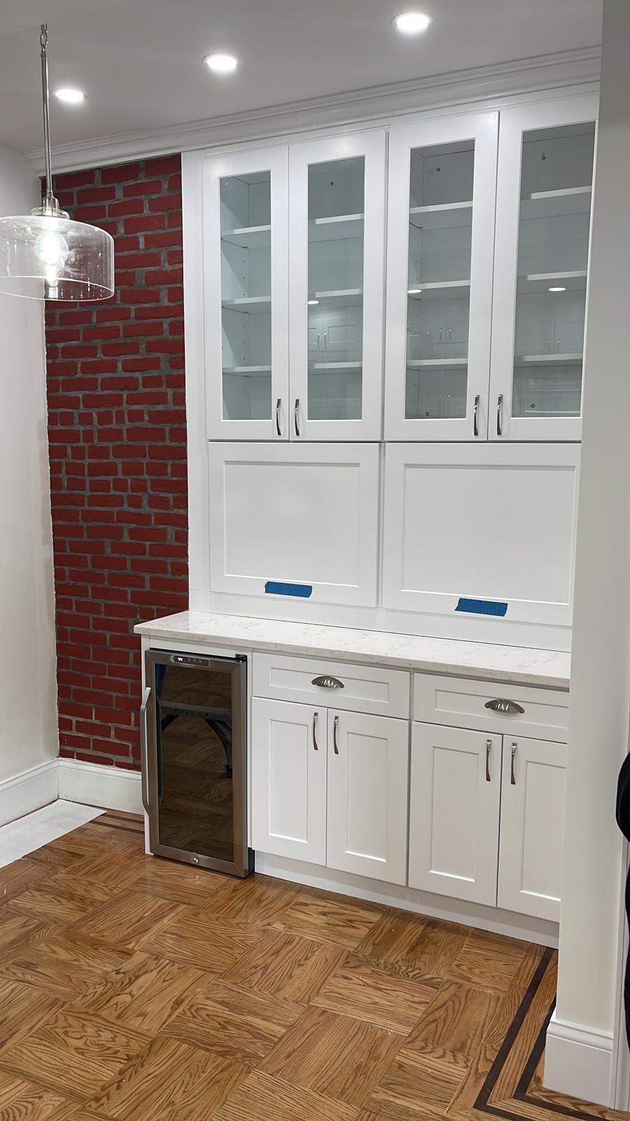 A kitchen with white cabinets and a brick wall