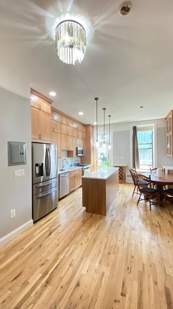 A kitchen with hardwood floors, stainless steel appliances, a refrigerator and a table
