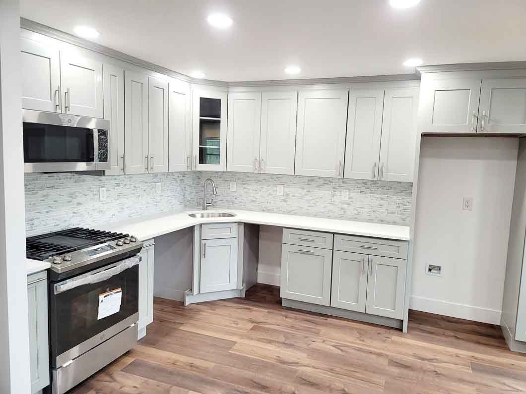 A kitchen with white cabinets, stainless steel appliances, and hardwood floors