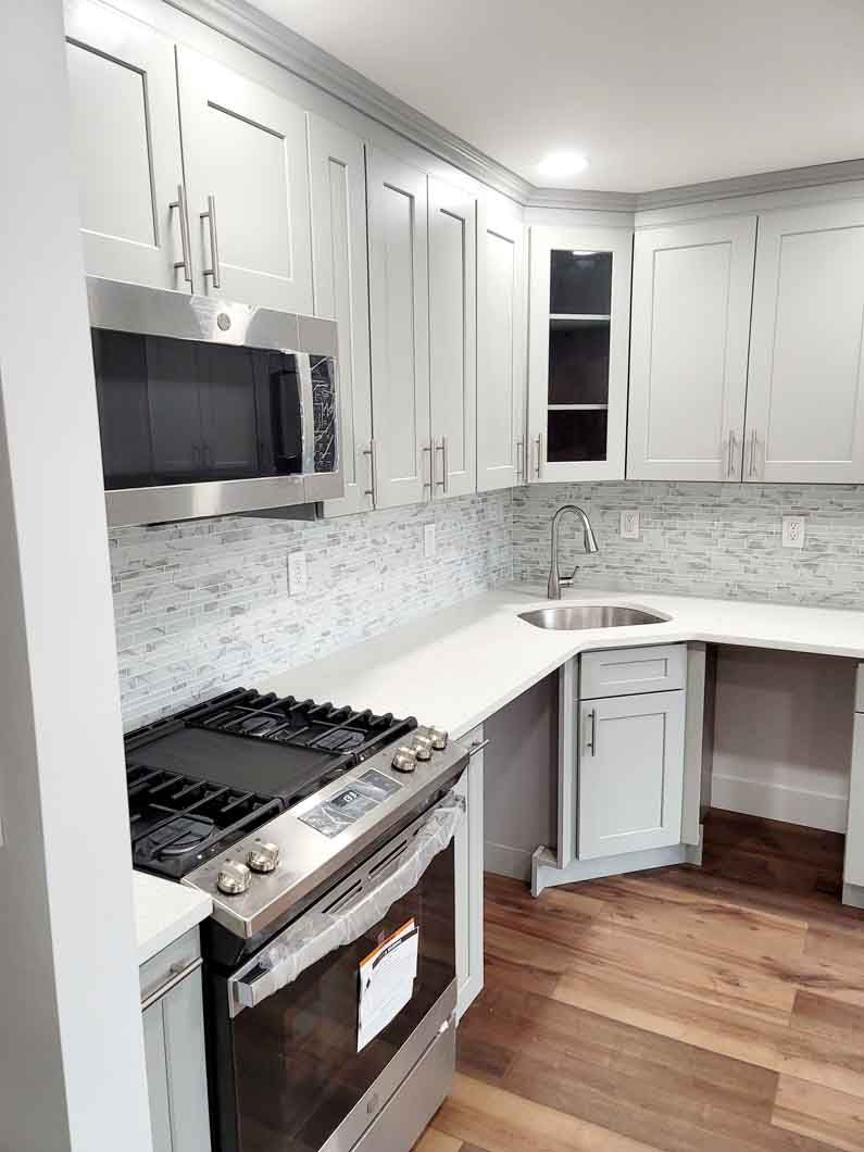 A kitchen with a stove, microwave, sink and cabinets