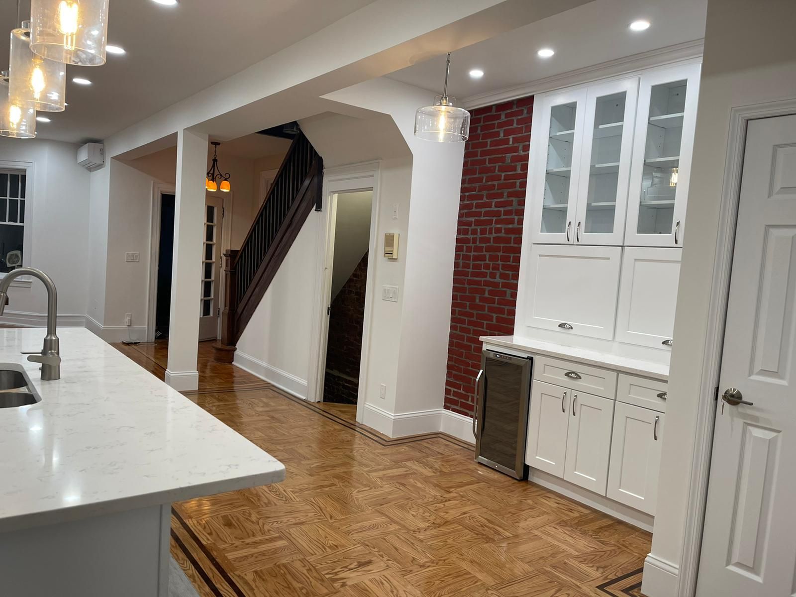 A kitchen with white cabinets and a brick wall
