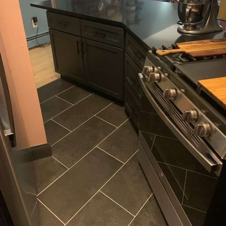 A kitchen with a stove top oven and black cabinets