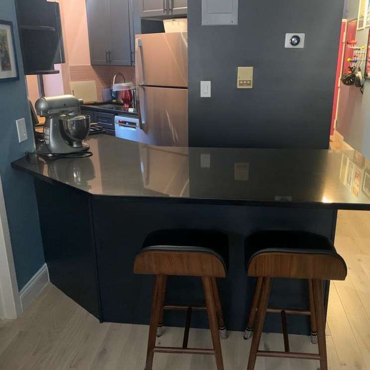 A kitchen with a black counter top and two stools