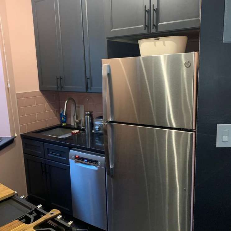 A kitchen with a stainless steel refrigerator and black cabinets