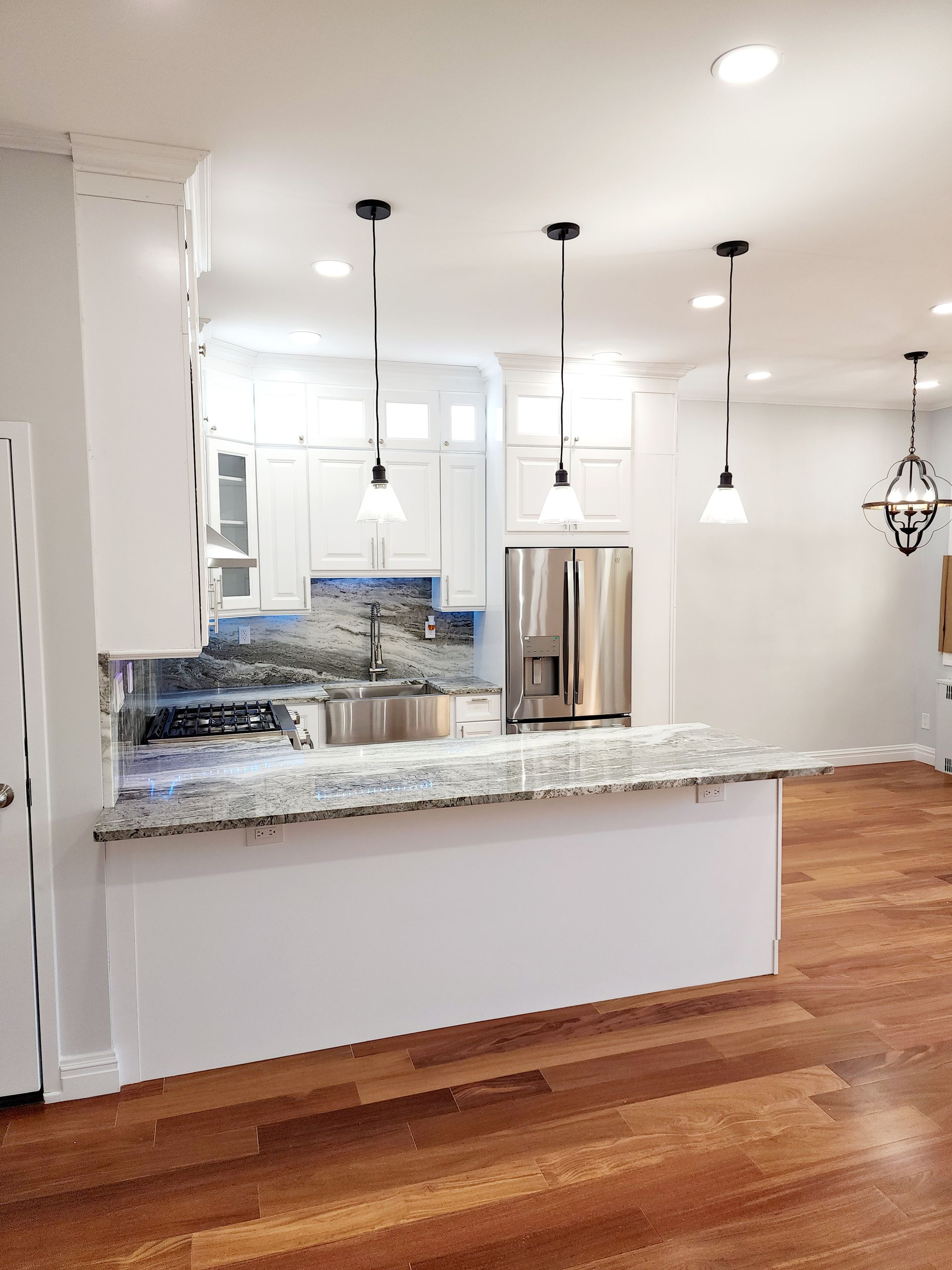 A kitchen with white cabinets, granite counter tops, stainless steel appliances and hardwood floors