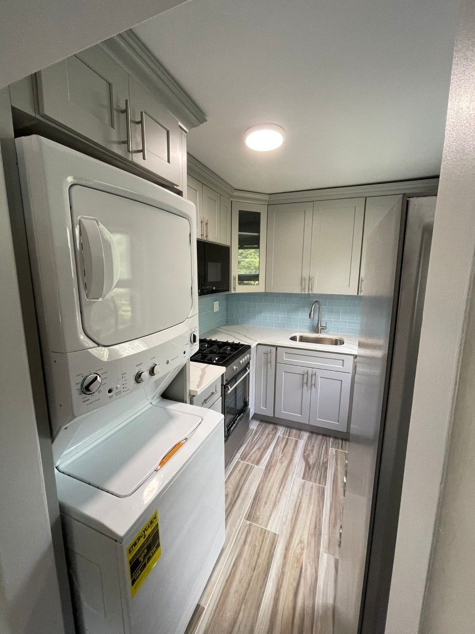 A kitchen with a washer and dryer and a microwave