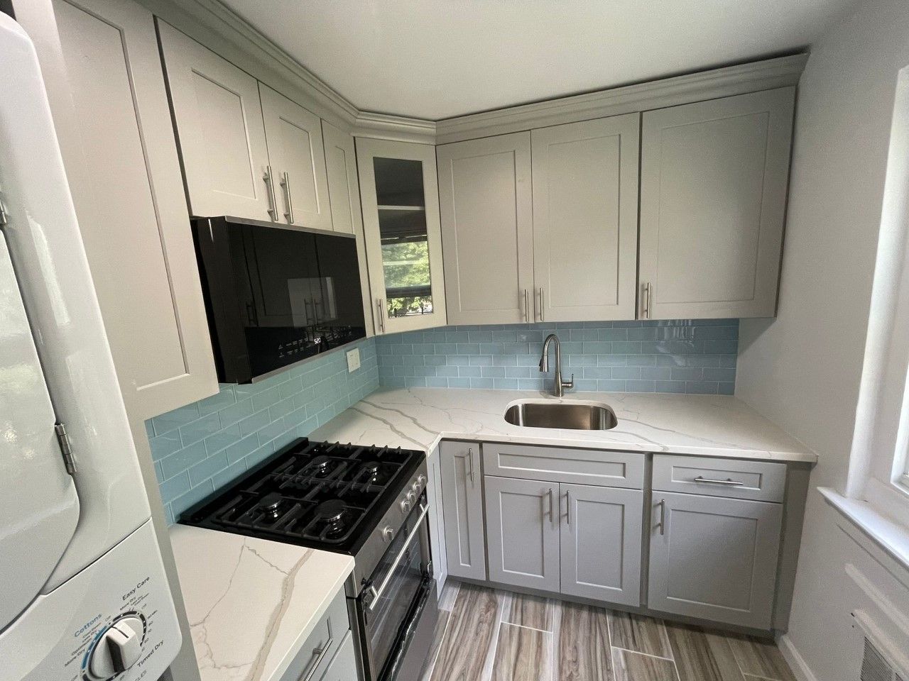 A kitchen with white cabinets, a stove, a sink and a microwave