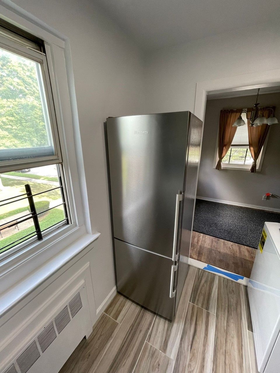 A stainless steel refrigerator is sitting in a kitchen next to a window