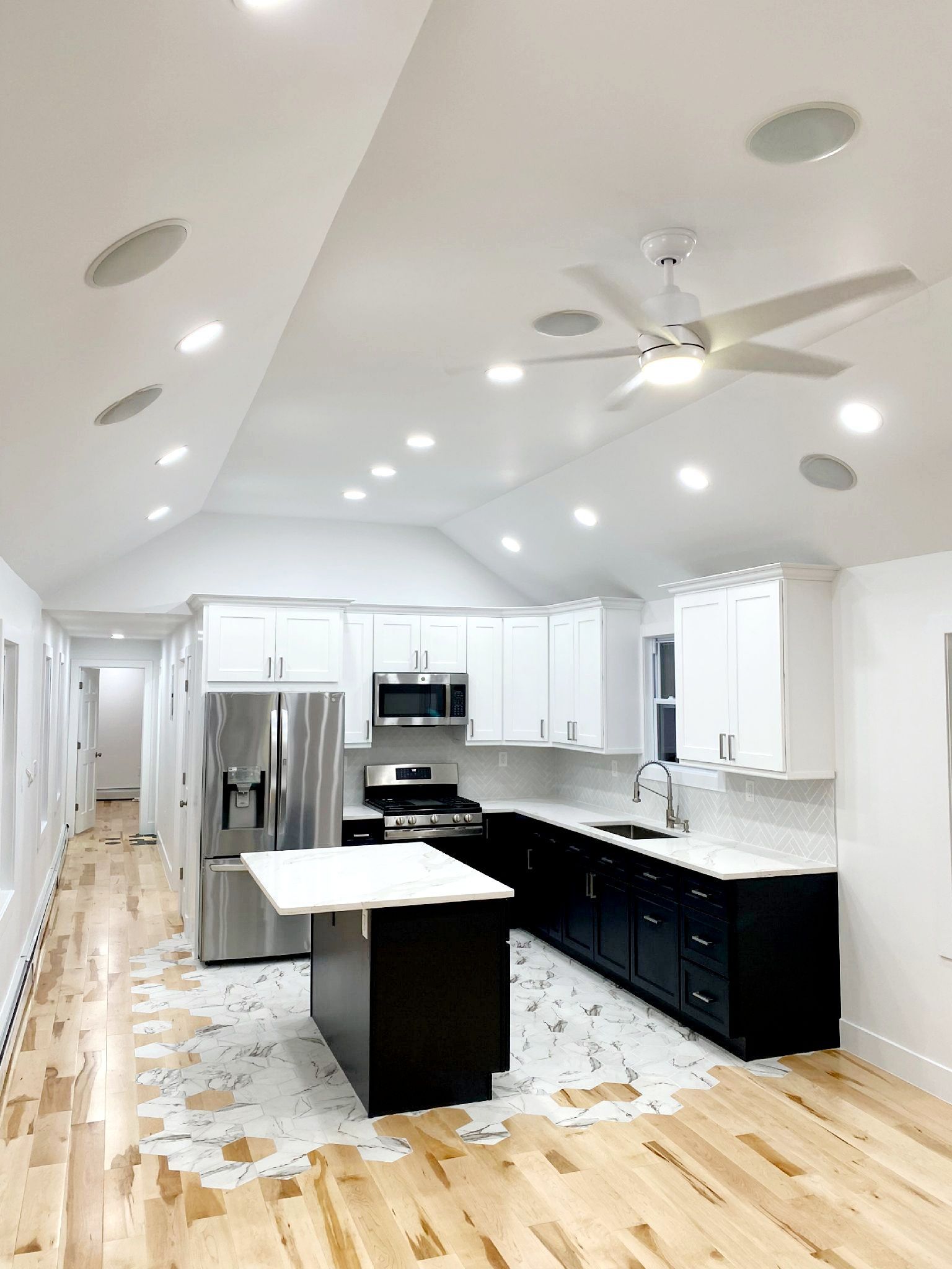 A kitchen with white cabinets, stainless steel appliances and a ceiling fan