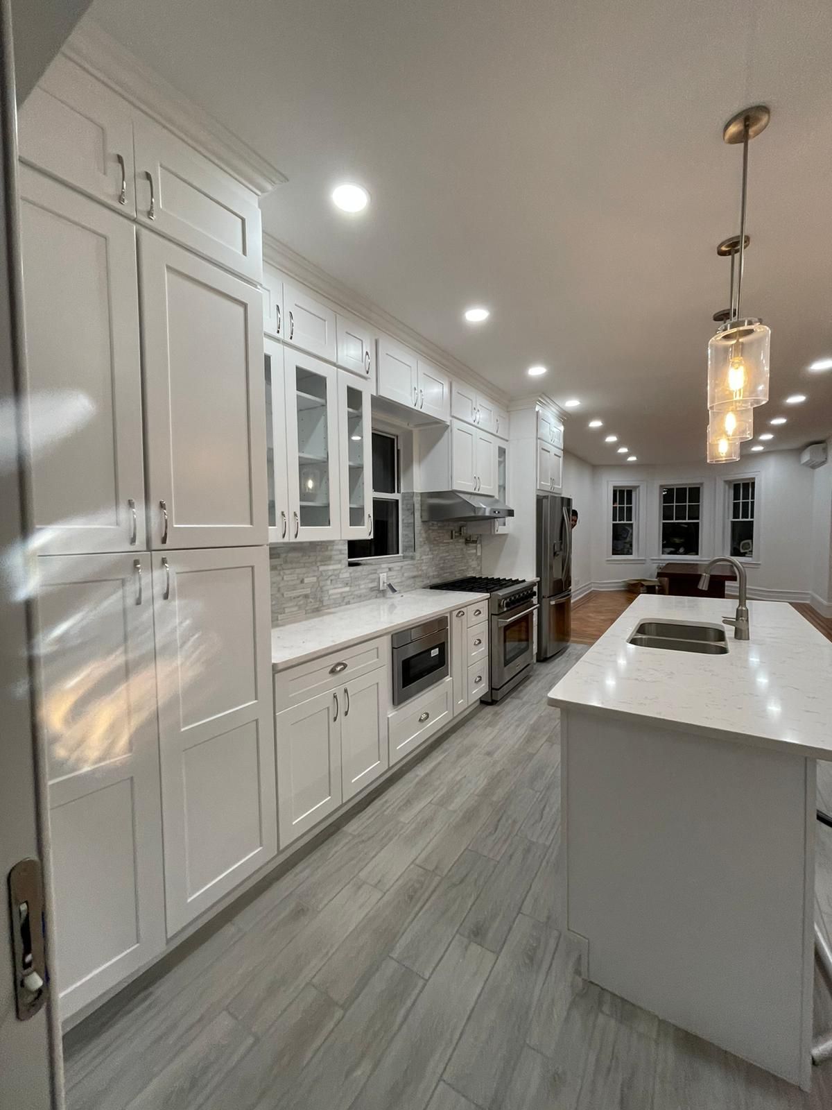 A kitchen with white cabinets, stainless steel appliances, and a large island