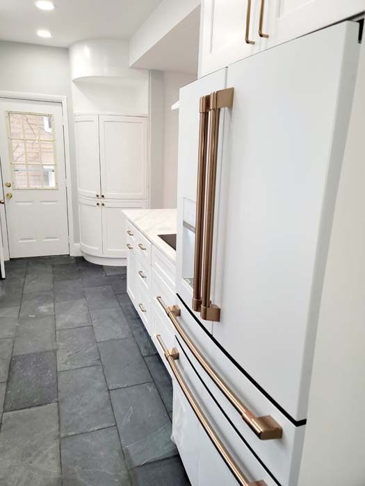 A kitchen with white cabinets and a white refrigerator