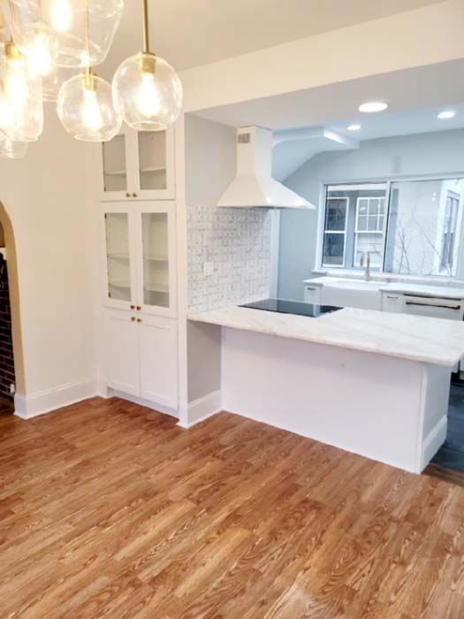 An empty kitchen with hardwood floors and white cabinets