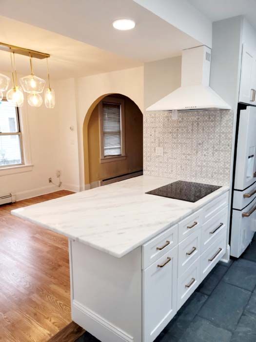 A kitchen with white cabinets and a stove top oven